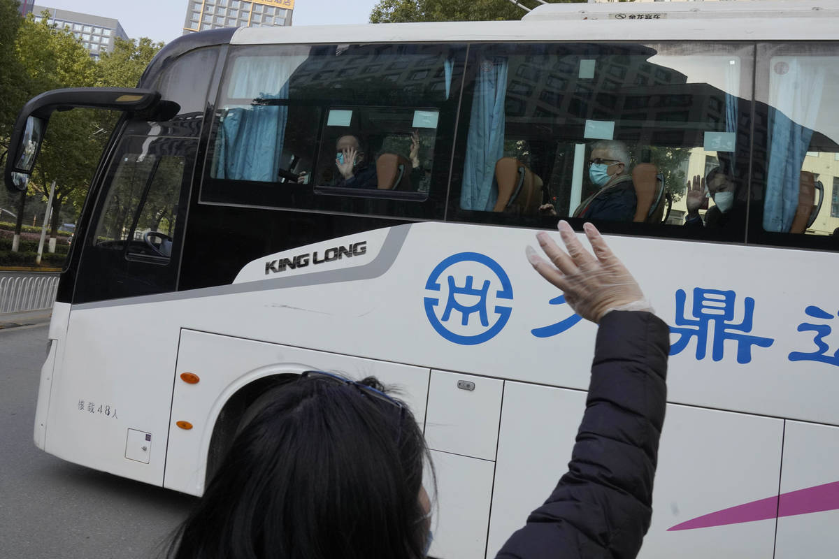 Workers wave to the team of experts from the World Health Organization who ended their quaranti ...