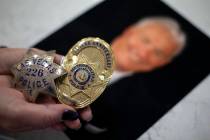 Kathy Karstedt holds her late husband's police badges over a photo of him at her home on Tuesda ...