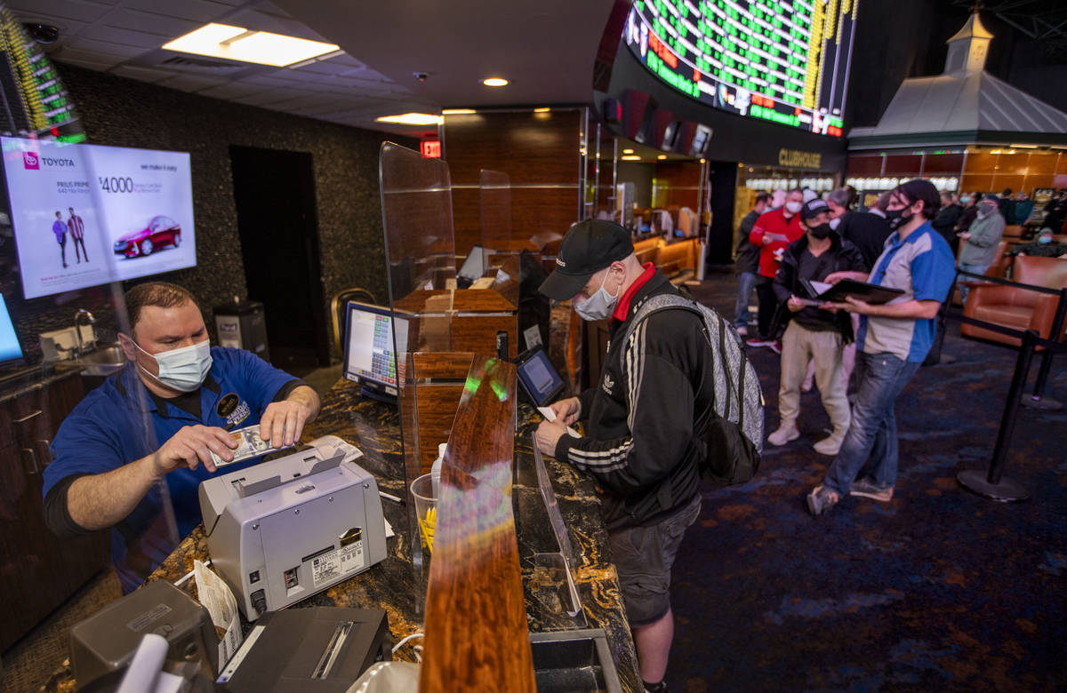 Mike Iannone, left, counts cash placed by a bettor as the Westgate sportsbook posts hundreds of ...