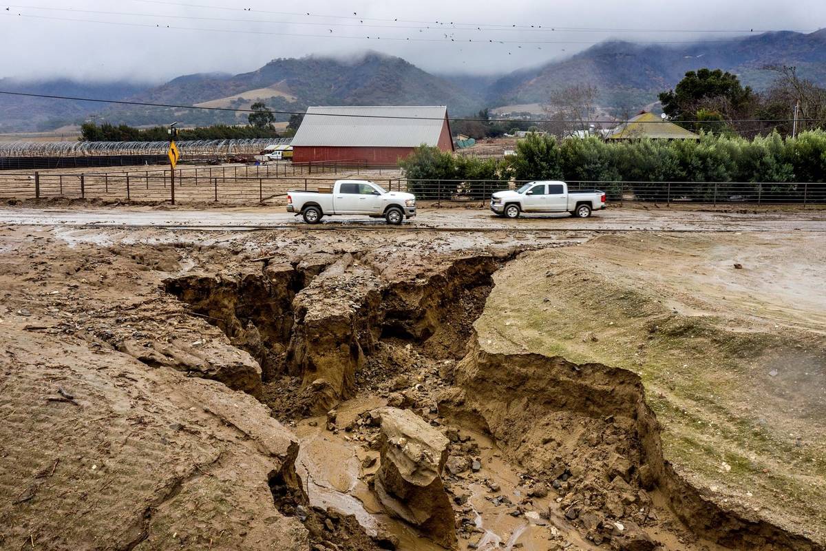 Trucks drive along River Rd. where heavy rains have caused mudslides and flooding near Salinas ...