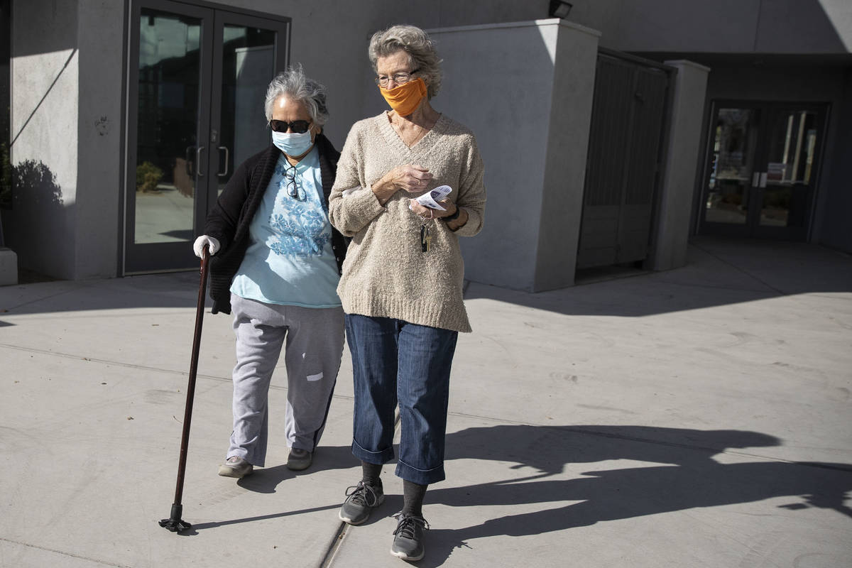 Carmen Mathis, 80, left, is assisted to her car by her friend Gail Smith, 81, after getting the ...