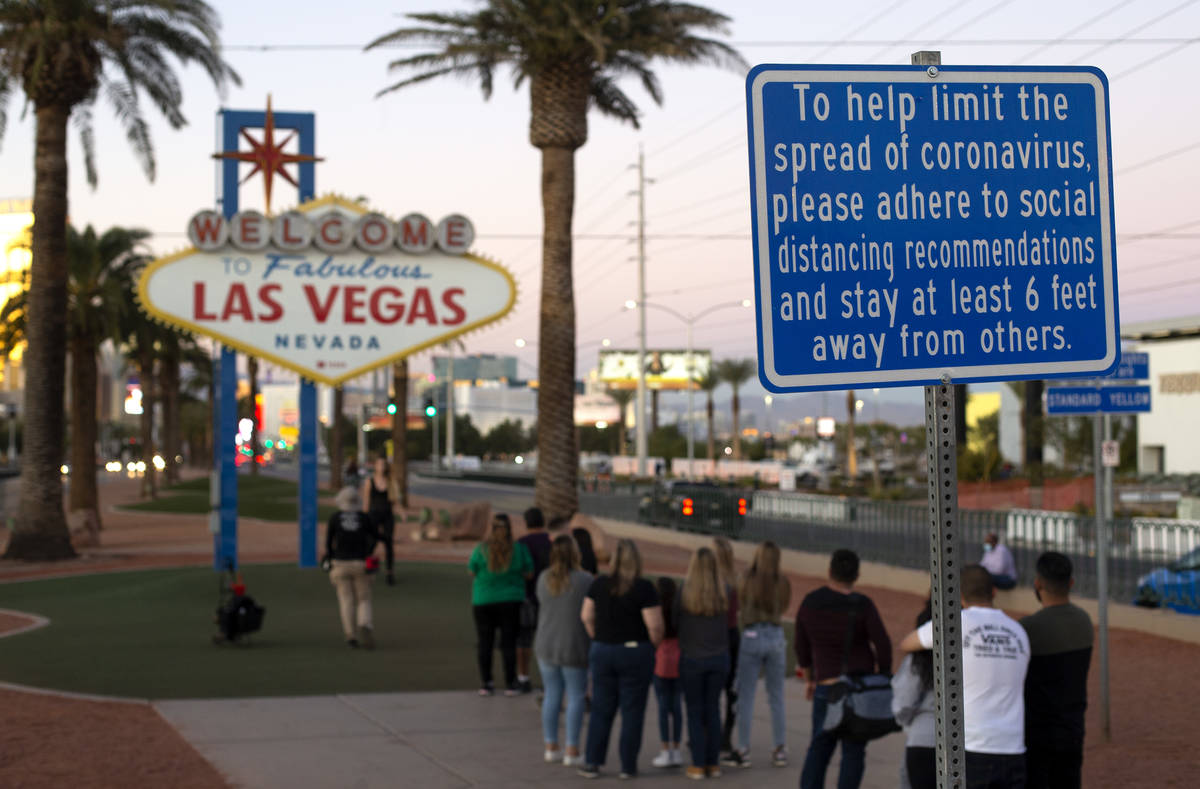 A sign asks visitors to stand apart to prevent the spread of coronavirus as they wait in line t ...