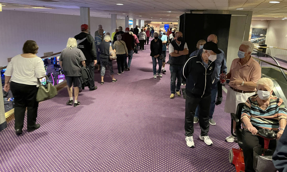 People wait in line for a COVID-19 vaccination at a Clark County and Southern Nevada Health Dis ...