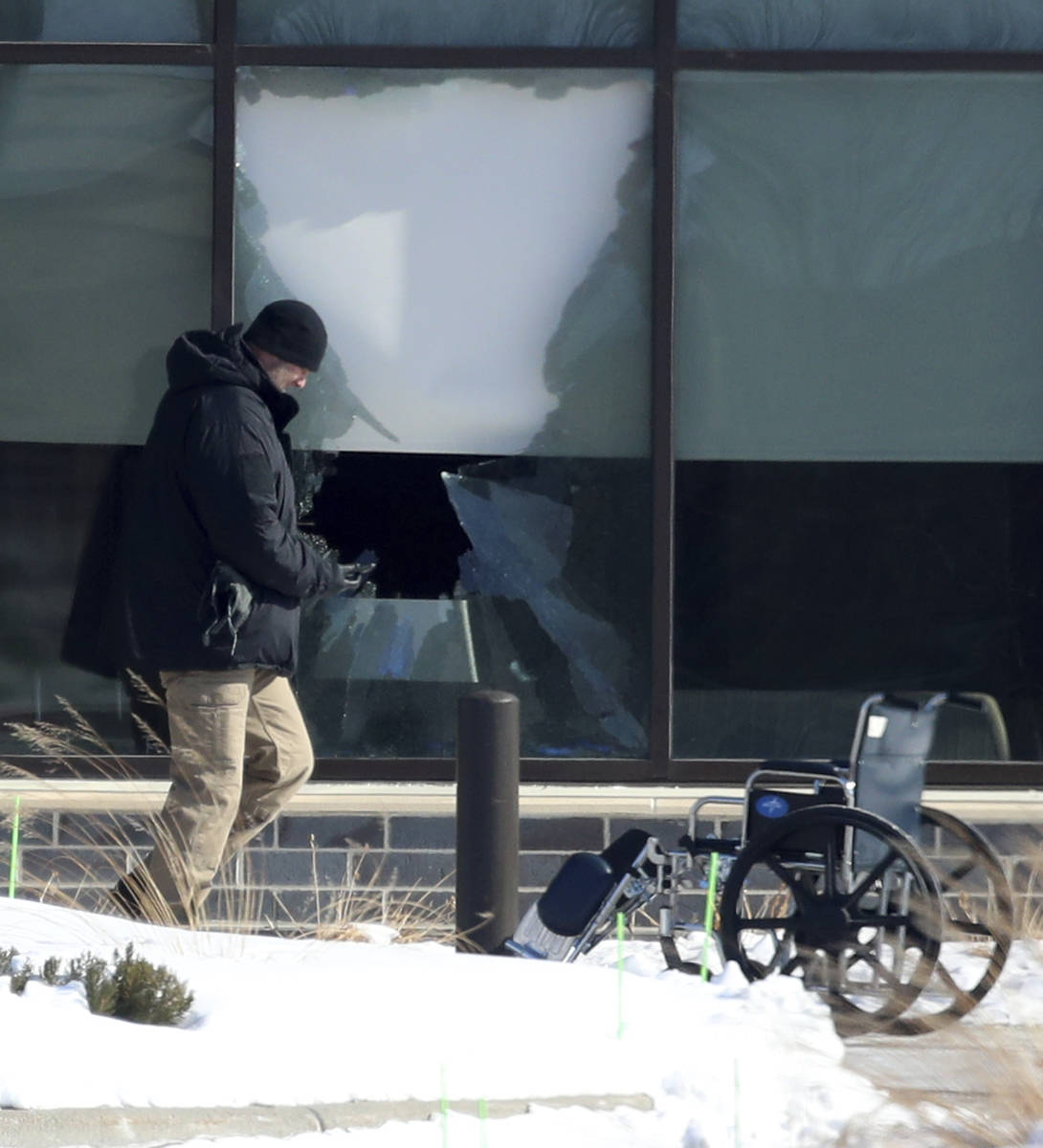 Law enforcement personnel walk past a broken window outside of the Allina Health clinic, Tuesda ...
