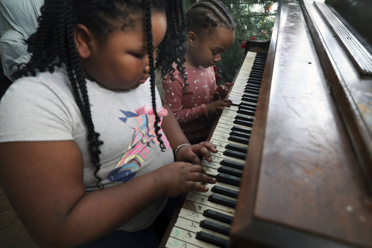 Brittani, left, and Lear Preston play the piano in their living room after their virtual school ...