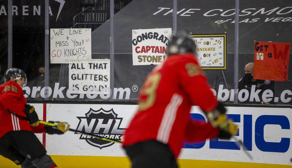 Golden Knights players skate past signs during warm ups before the first period of an NHL game ...