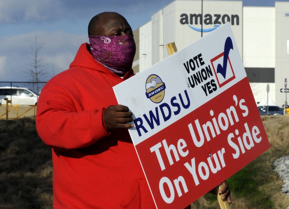 Michael Foster of the Retail, Wholesale and Department Store Union holds a sign outside an Amaz ...