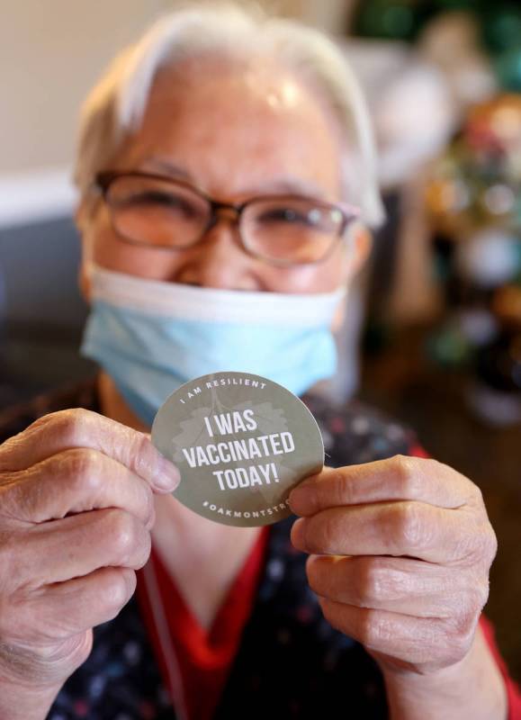 Akiko Byers, 80, shows her "I was vaccinated today!" sticker after receiving the Pfiz ...