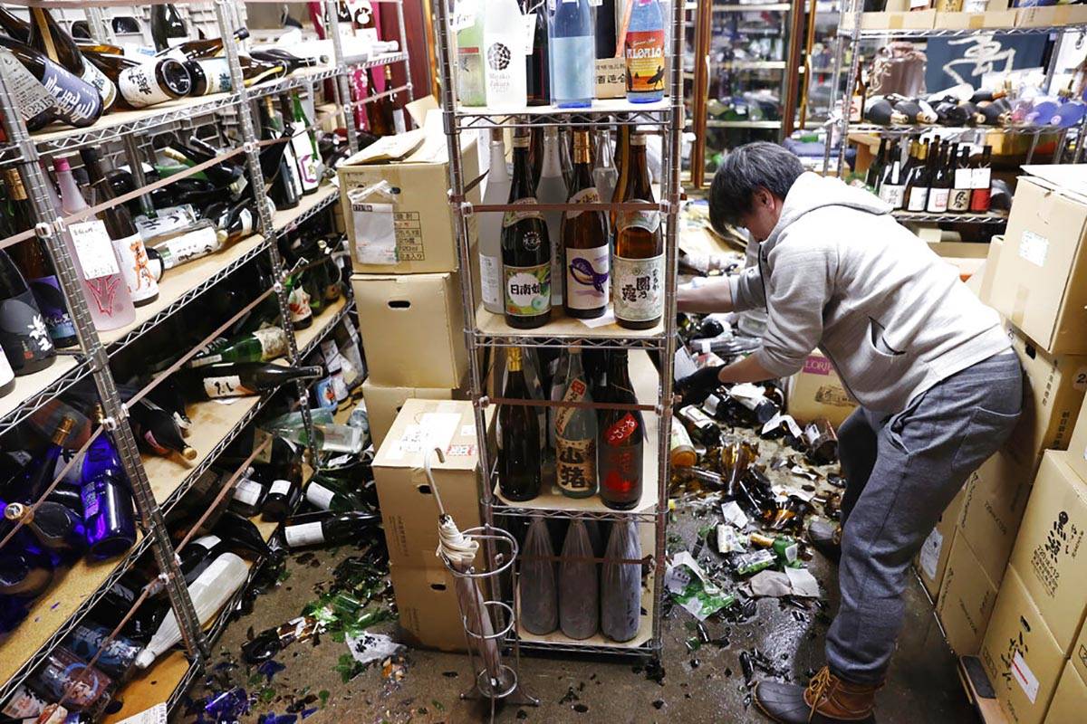 A liquor shop's manager clears the damaged bottles following an earthquake in Fukushima, northe ...
