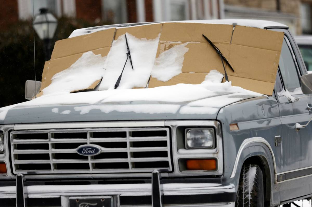 A resident of Tulsa takes precautions against an icy windshield as a winter storm moves into no ...