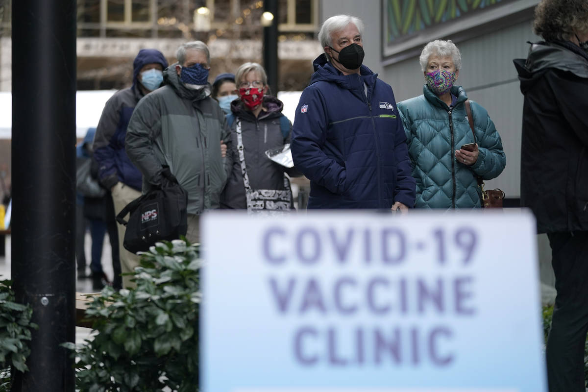 In a Jan. 24, 2021, file photo, people stand near a sign as they wait in line to receive the fi ...