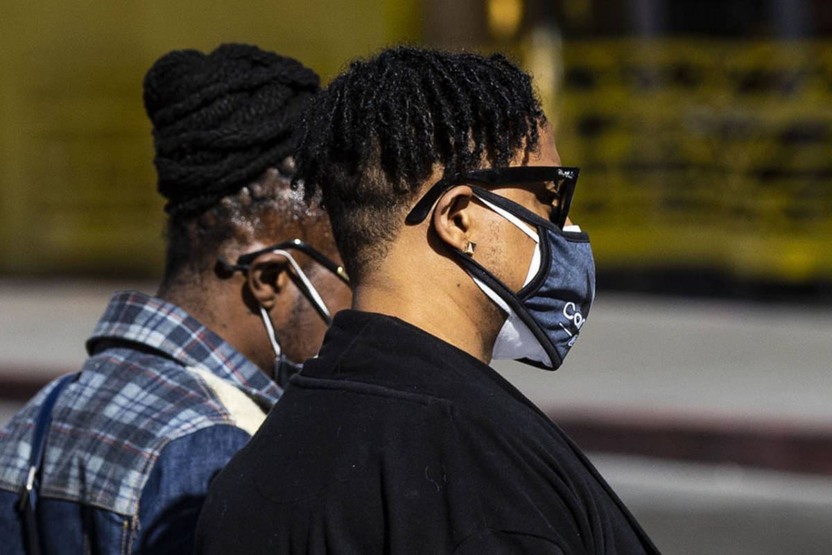 A person wearing double masks crosses Fourth Street at Fremont Street in downtown Las Vegas on ...