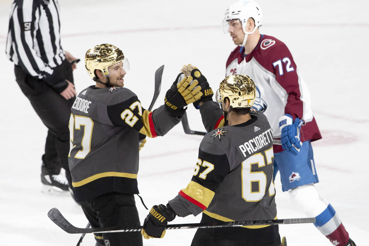 Golden Knights defenseman Shea Theodore (27) congratulates Golden Knights left wing Max Paciore ...