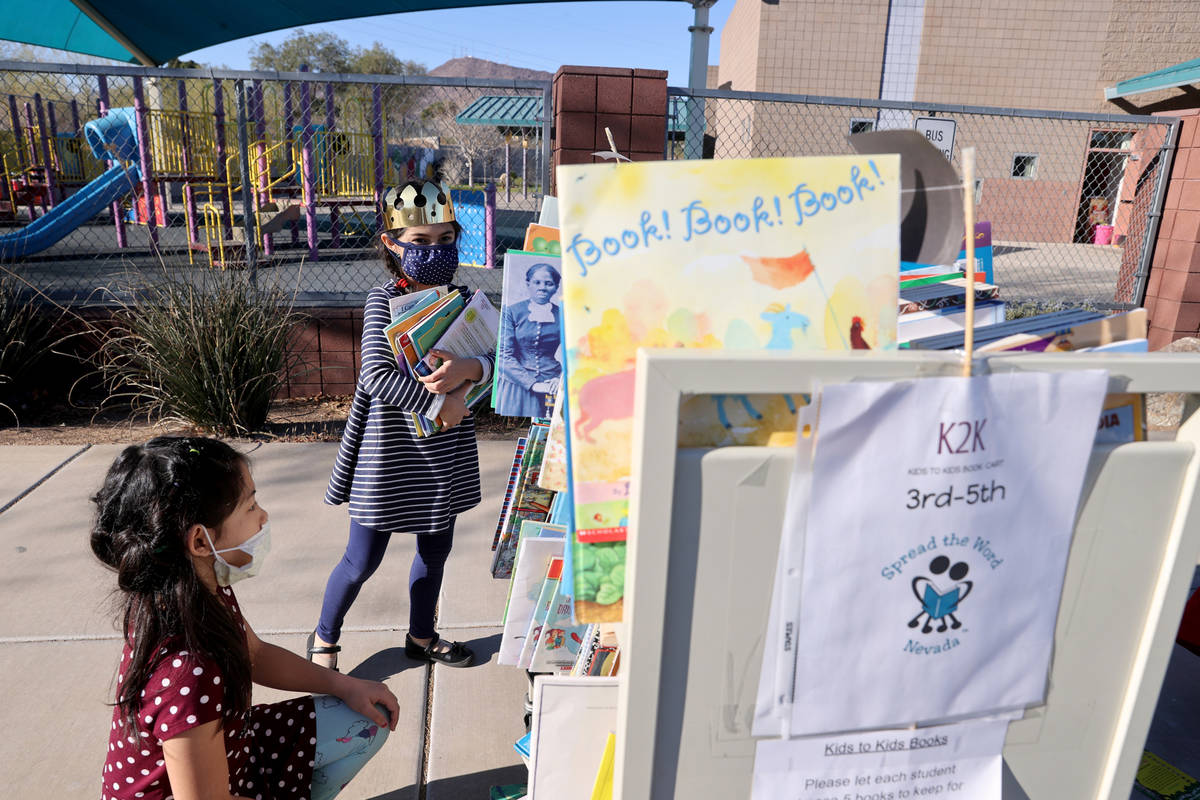 Maiyah Concepcion, 8, left, and Amaliya Yusupova, 7, choose books during a school supply distri ...