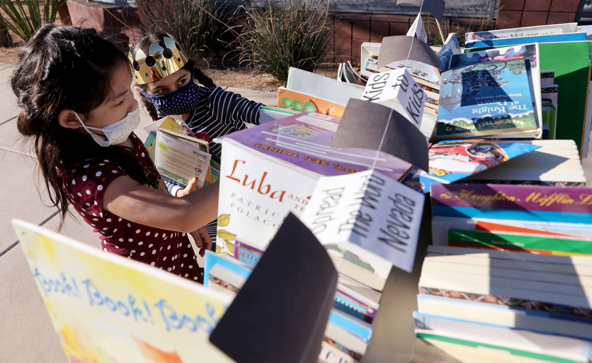 Maiyah Concepcion, 8, left, and Amaliya Yusupova, 7, choose books during a school supply distri ...