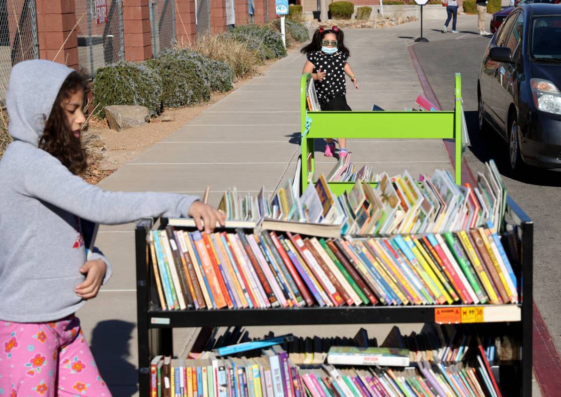 Second grader Thelma Castro-Rodriguez, 8, chooses books as first grader Tatiana Melgoza, 6, run ...
