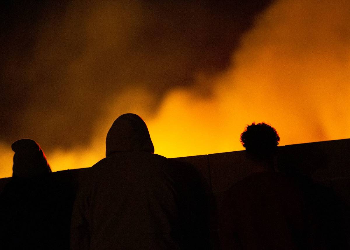 Onlookers watch a brush fire at Clark County Wetlands Park on Wednesday, Feb. 17, 2021, in Las ...