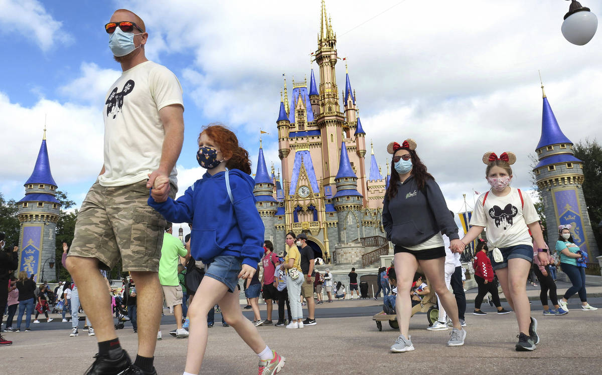 FILE - IN this Dec. 21, 2020 file photo, A family walks past Cinderella Castle in the Magic Kin ...