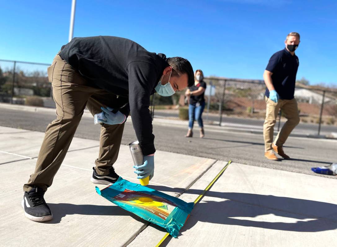 Chris Zayas, Goolsby, preschool teacher assistant, sprays social distancing markers as Danny Ei ...