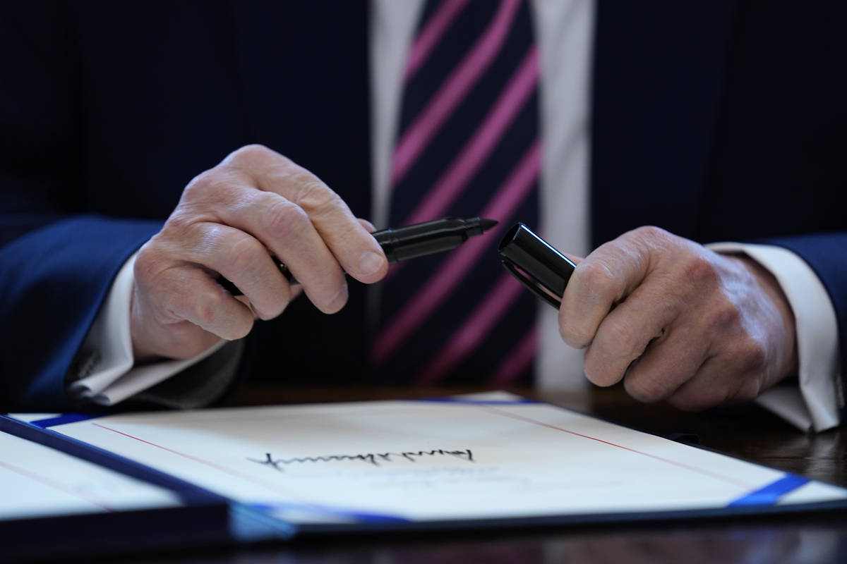 FILE - In this April 24, 2020, file photo President Donald Trump puts the cap on a pen after si ...