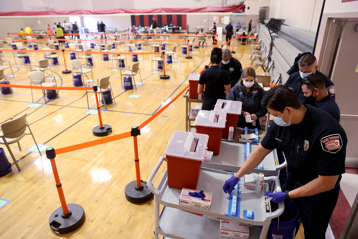 Las Vegas Fire Department firefighter Enrique Lopez, right, prepares for a COVID-19 vaccine cli ...