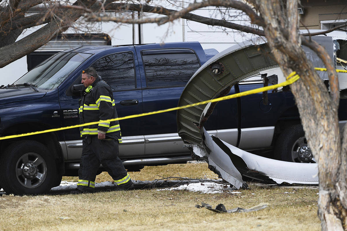 A North Metro firefighter walks past a large piece of an airplane engine in the front yard of a ...
