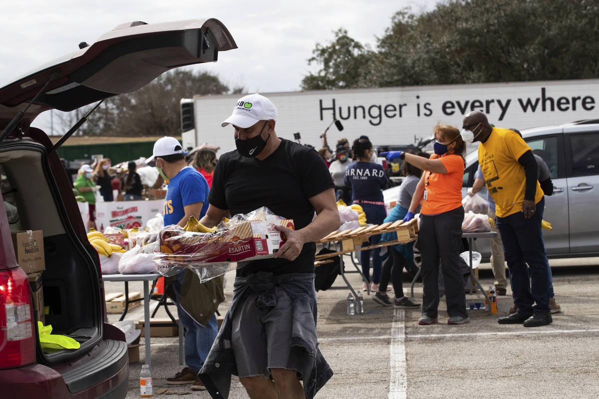 Houston Food Bank employee Enrique Albi approaches a vehicle to load food during a food distrib ...