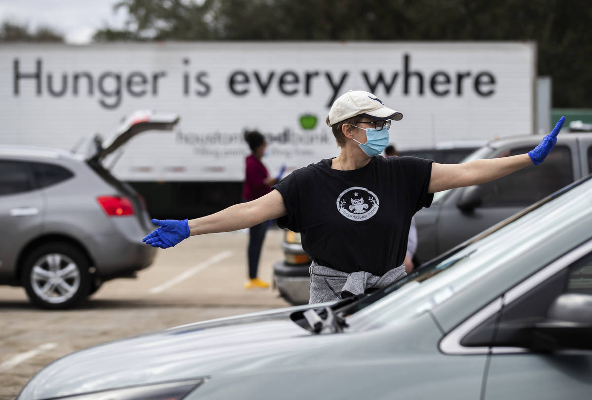 Houston Food Bank volunteer Cecilie Tindlund directs traffic during a food distribution event a ...