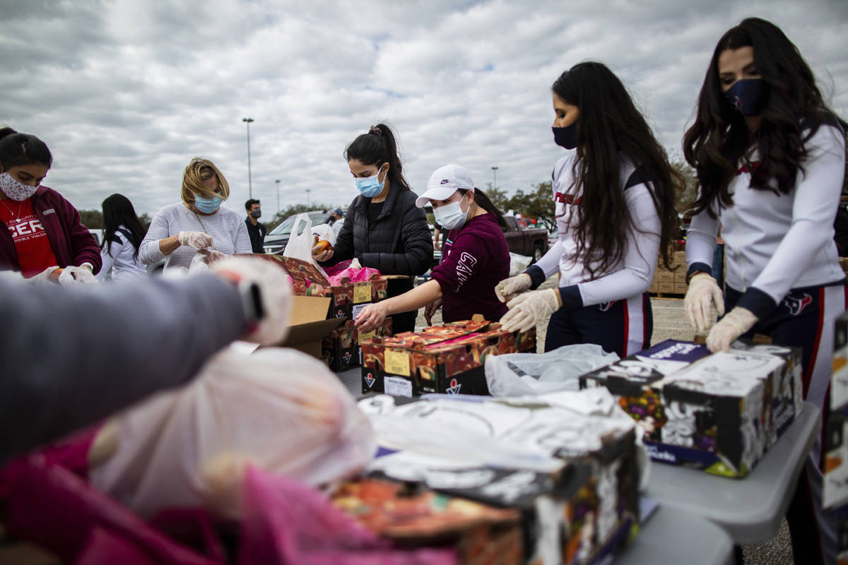 Texans Cheerleaders and other volunteers pack food to distribute to hundreds of people picking ...