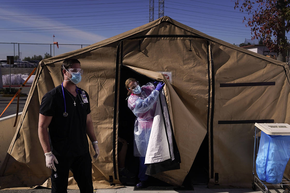 FILE - In this Dec. 22, 2020, file photo, registered nurse Keith Robinson, right, watches as fe ...