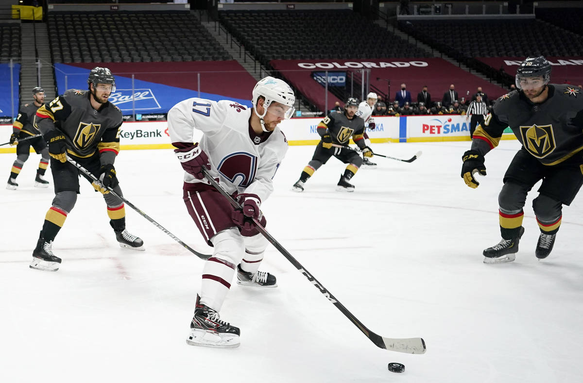 Colorado Avalanche center Tyson Jost, center, collects the puck as Vegas Golden Knights defense ...