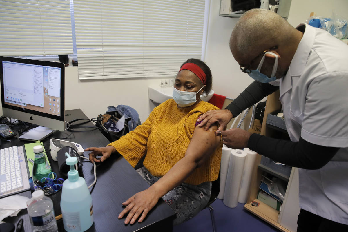 Family doctor Joel Valendoff administrates the AstraZeneca COVID-19 vaccine to a woman at his o ...