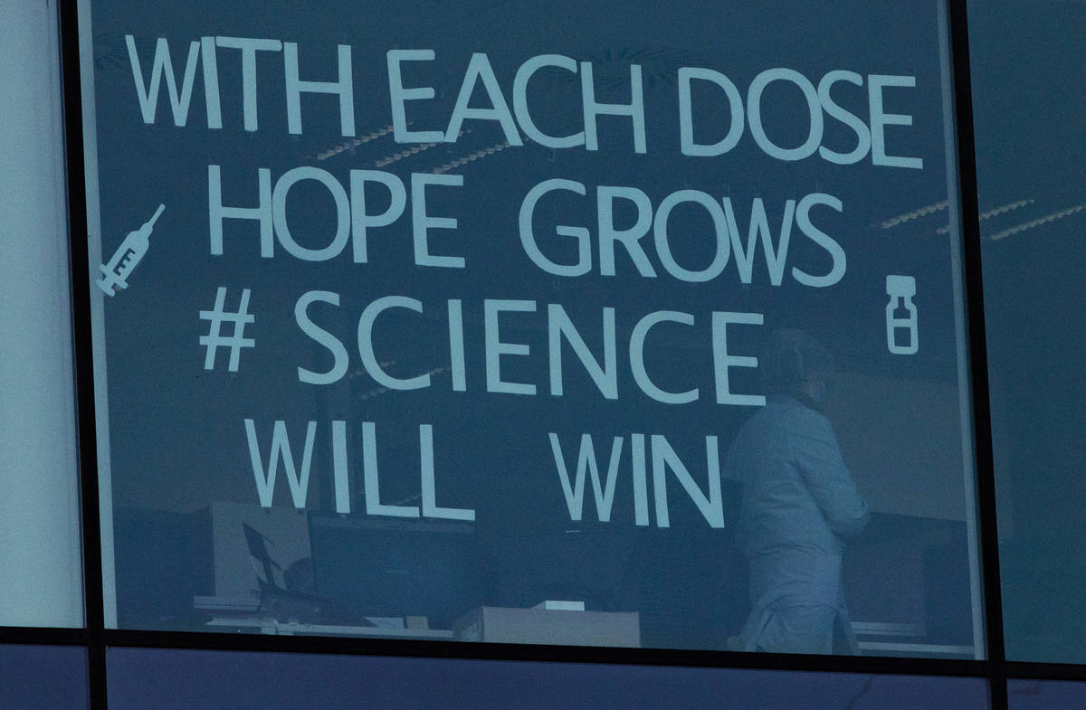 An employee works behind a window with a message taped to it at Pfizer Manufacturing in Puurs, ...
