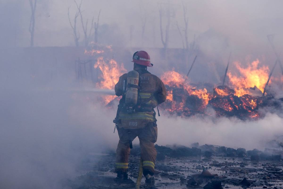 A firefighter battles a fire at a commercial yard in Compton, Calif., on Friday, Feb. 26, 2021. ...