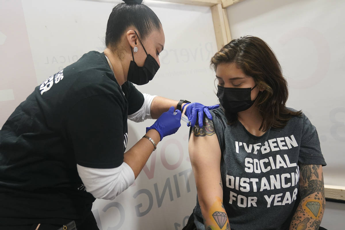 Denise Padilla, right, an instructor at the culinary school at Eva's Village, is vaccinated in ...