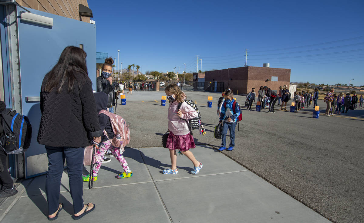 Teachers and other staff members lead students inside from the playground at Goolsby Elementary ...