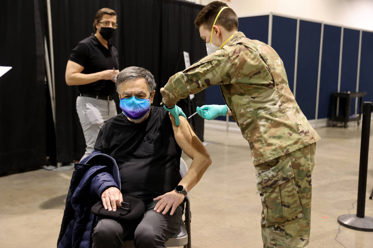 Nevada National Guard Spc. Katherine Deskins administers the Pfizer vaccine shot to Andy Perla, ...