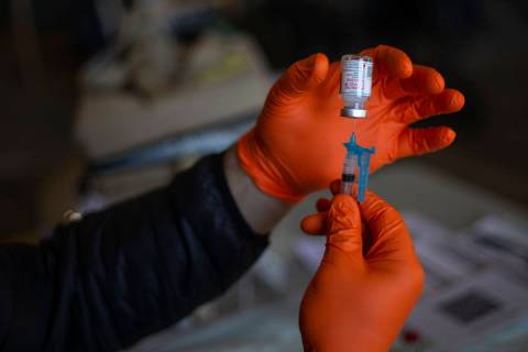 Paramedic Craig Johnson draws a dose of the Moderna COVID-19 vaccine in preparation for Guardia ...