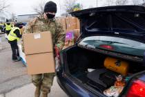 Staff Sgt. Mike Schuster loads two produce boxes into a car at a food bank distribution by the ...