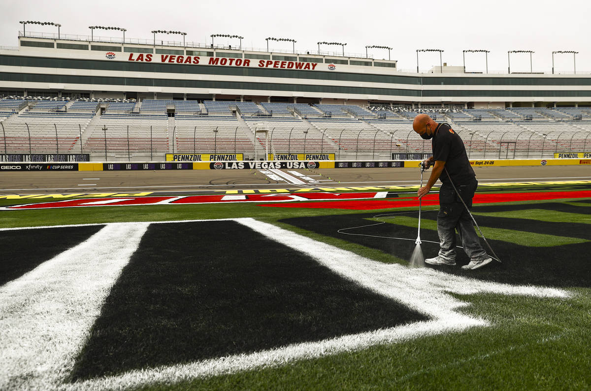 Dale Pantelakis, of Ananta Surfaces, paints logos on the infield grass ahead of the Pennzoil 40 ...