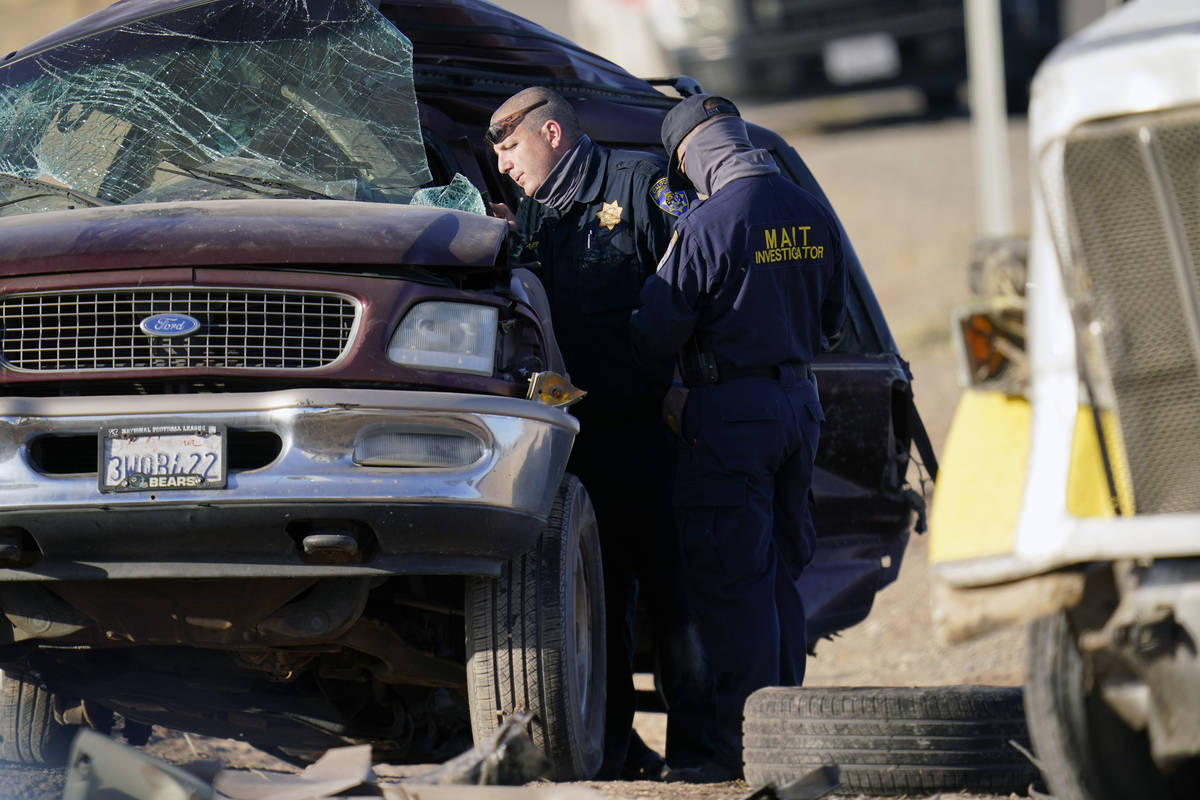 Law enforcement officers sort evidence and debris at the scene of a deadly crash in Holtville, ...