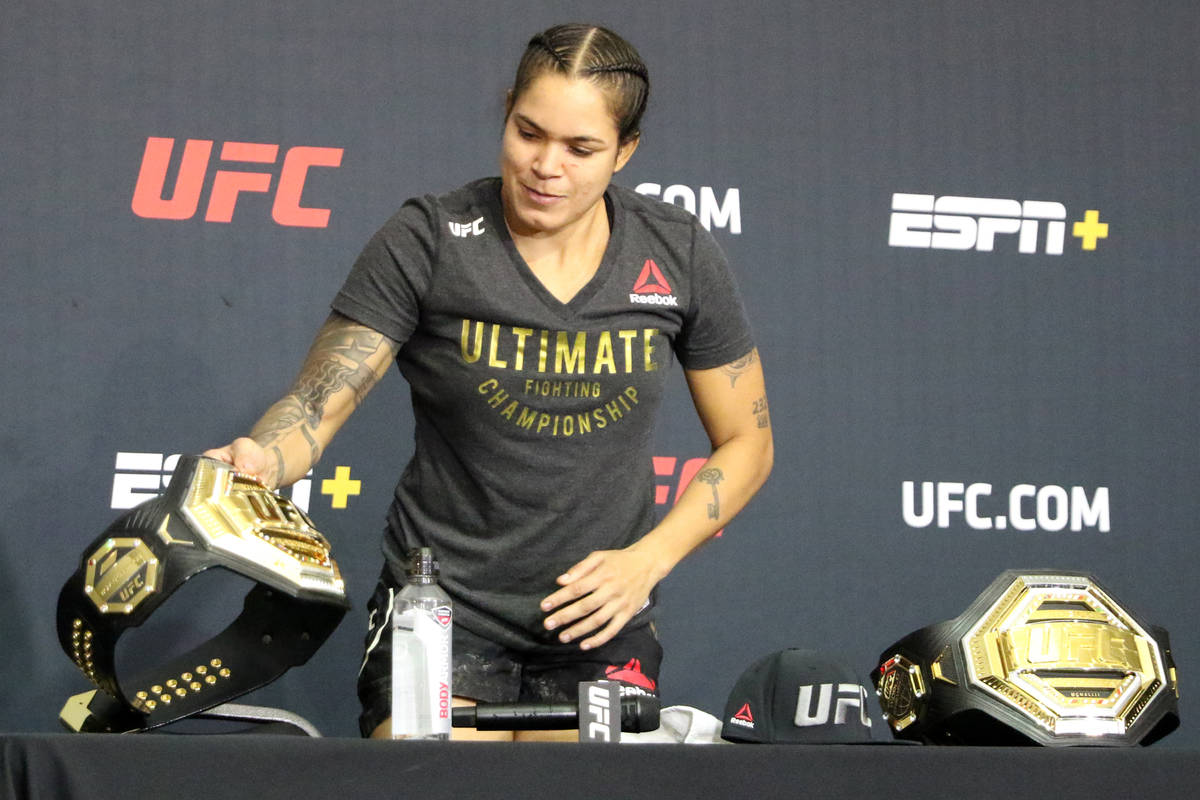 Two-division women's UFC champion Amanda Nunes picks up her title belt during a post-fight news ...