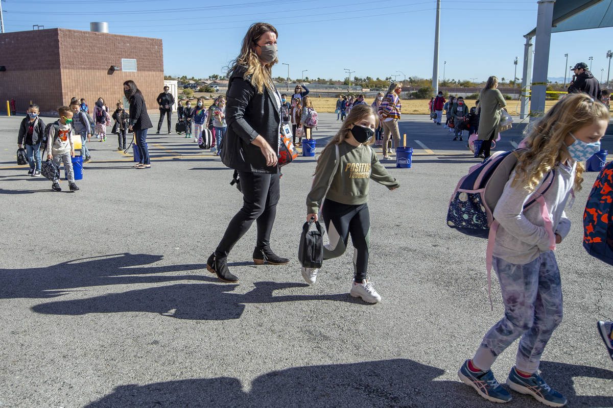 Teachers and other staff members lead students inside from the playground at Goolsby Elementary ...