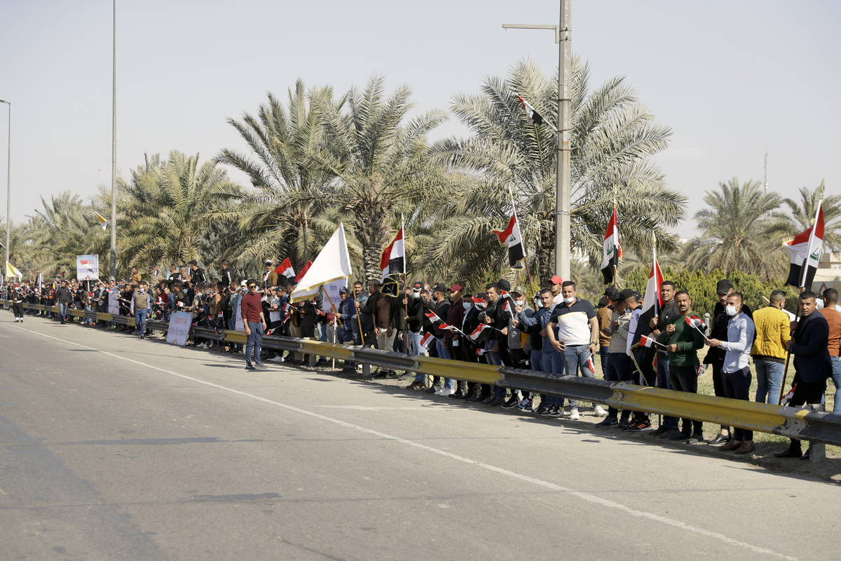 People stand by the road as they wait for Pope Francis, in Baghdad Iraq, Friday, March 5, 2021. ...