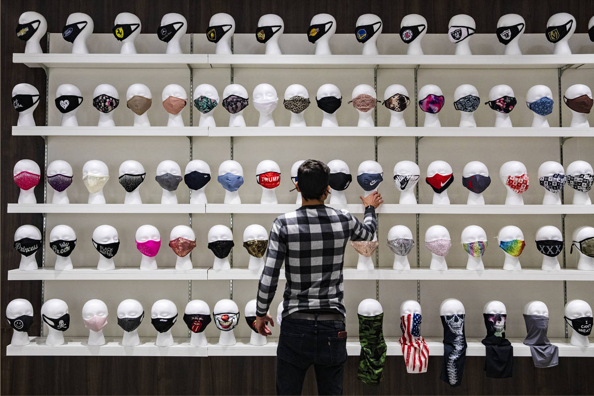 Salesperson Lucas Nascimento rearranges masks for sale at the COVID-19 Essentials store in the ...