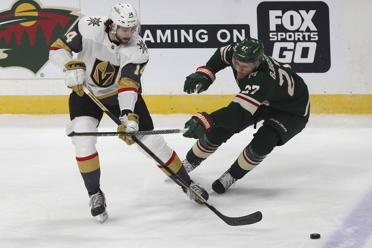 Vegas Golden Knights' Nicolas Hague (14) handles the puck against Minnesota Wild's Nick Bjugsta ...