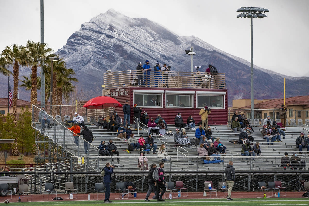 Fans are sprinkled in the stands with snow on the mountains as Faith Lutheran takes on Moapa Va ...