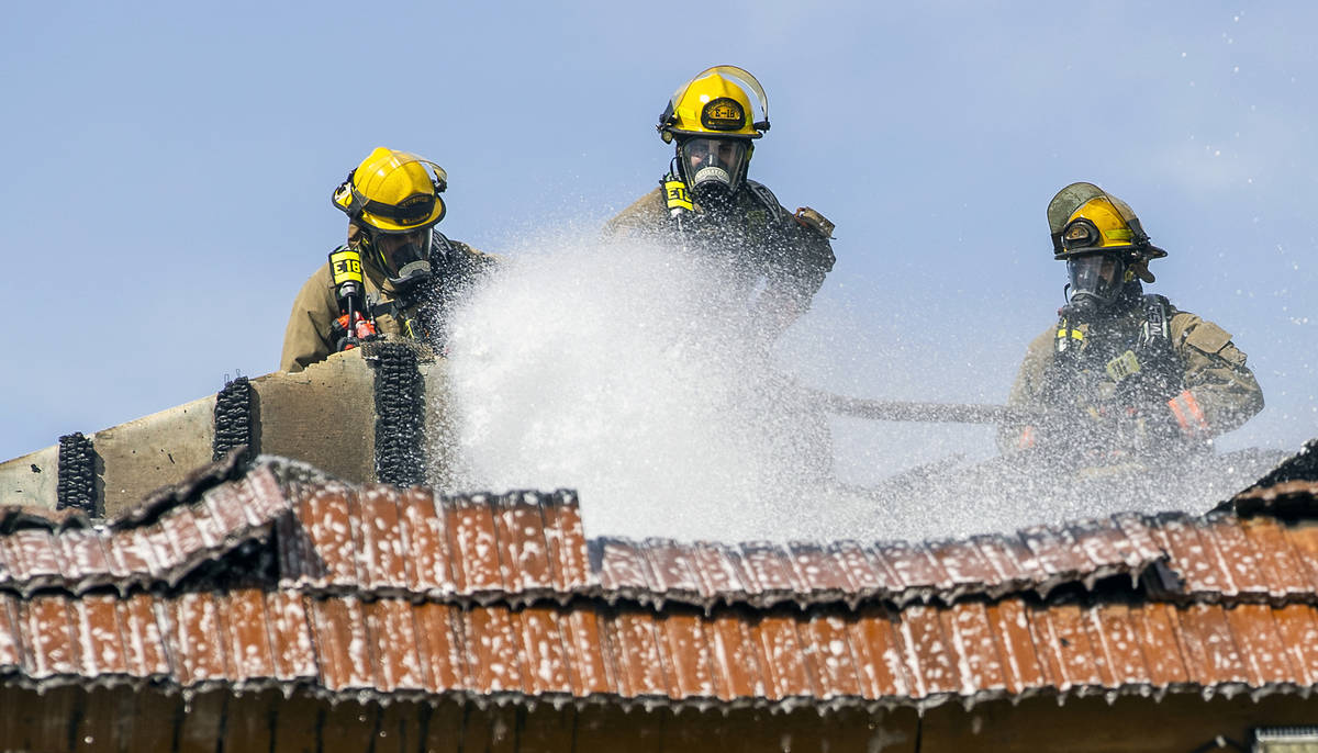 Clark County and Las Vegas Fire Department firefighters spray from atop of the roof as they wor ...