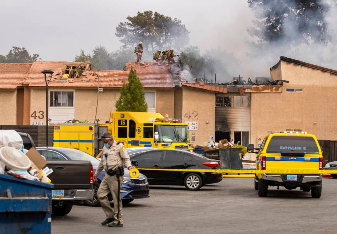 Police tape goes up as Clark County and Las Vegas Fire Department firefighters work from the ro ...