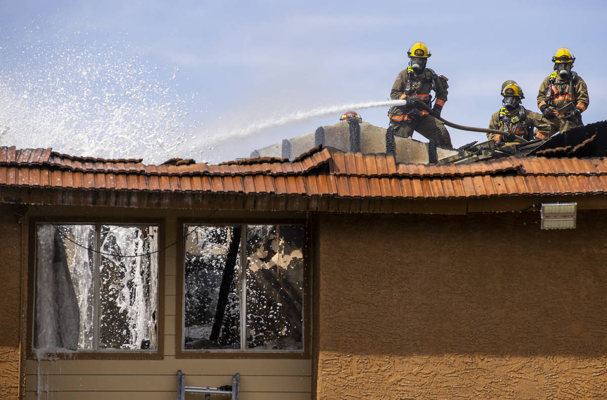 Clark County and Las Vegas Fire Department firefighters spray from atop of the roof as they wor ...